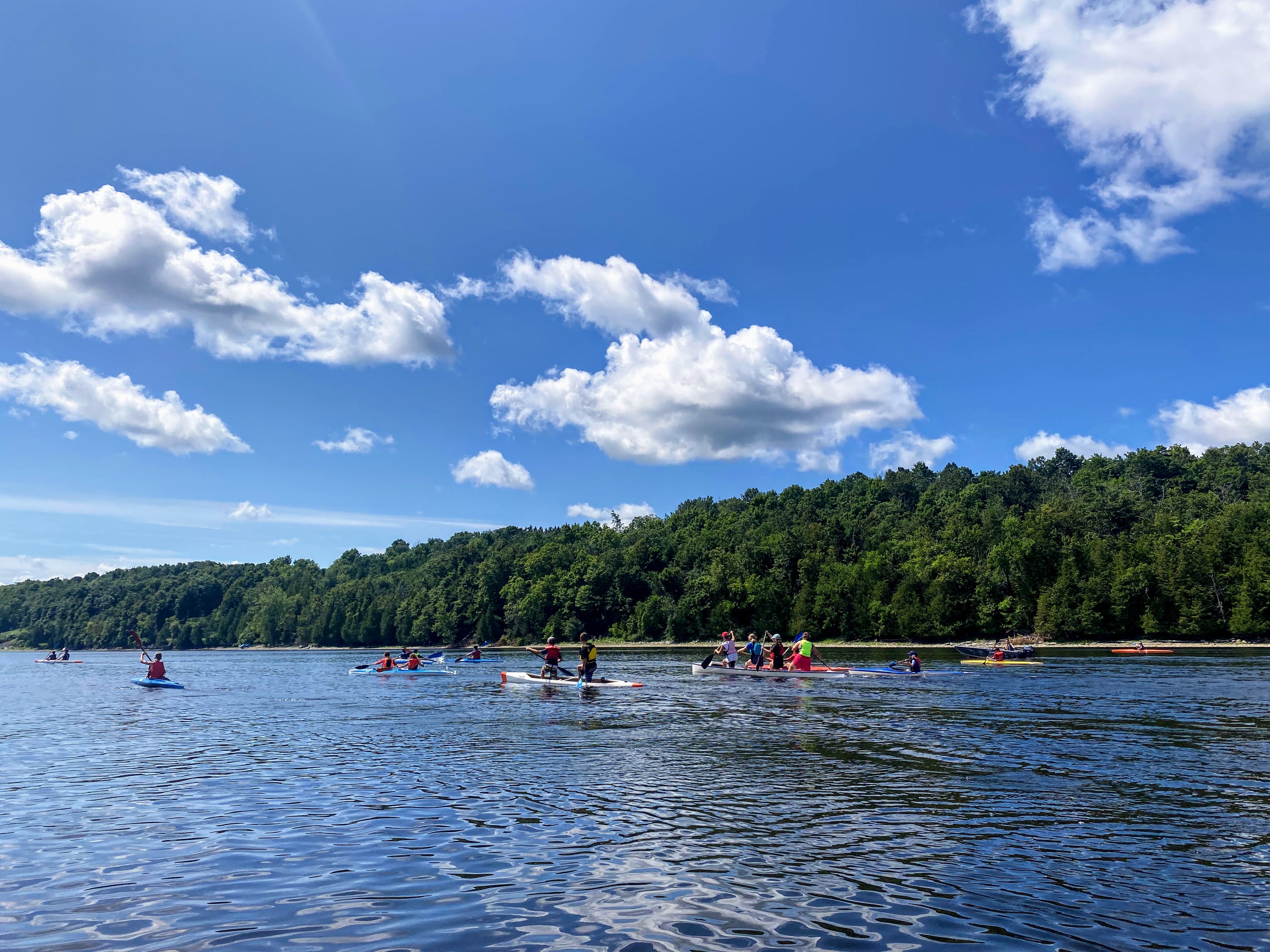 Large group of youth athletes paddling in sprint boats ranging from K1, K2, and C2 to C4 and more.
