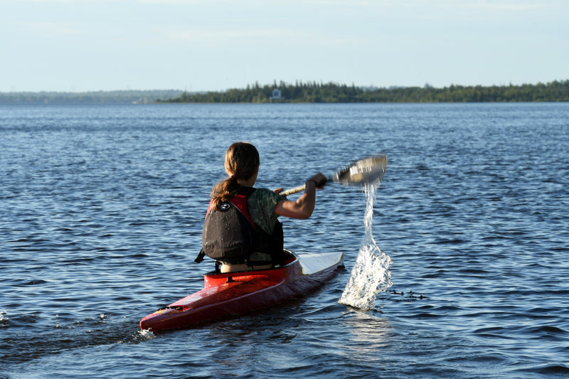 Athlete paddling away from dock in red K1.